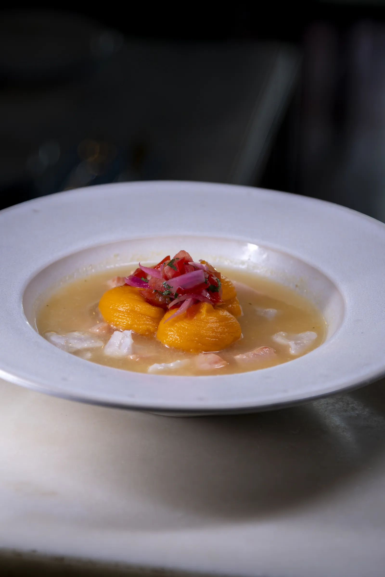 Prato de peixe cru com tomate e citrinos, em louça branca