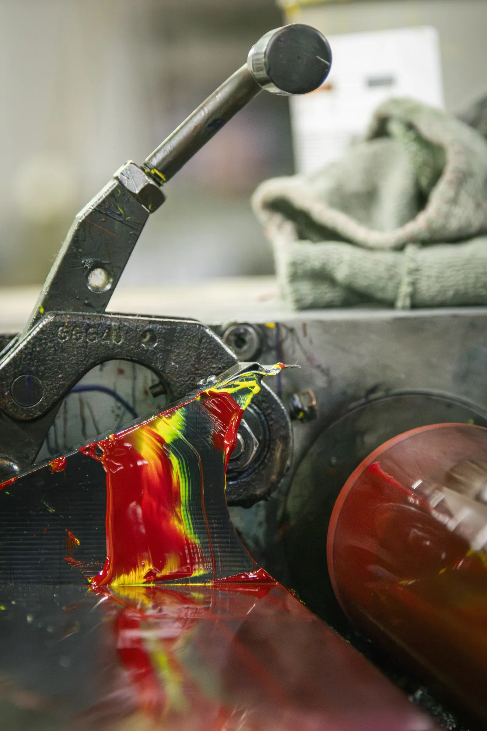 Tinta vermelha e amarela a escorrer no rolo de uma máquina de impressão